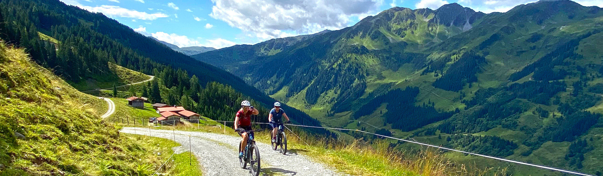 Mountainbiker auf Schotterweg mit weitem Blick in die Tiroler Berglandschaft