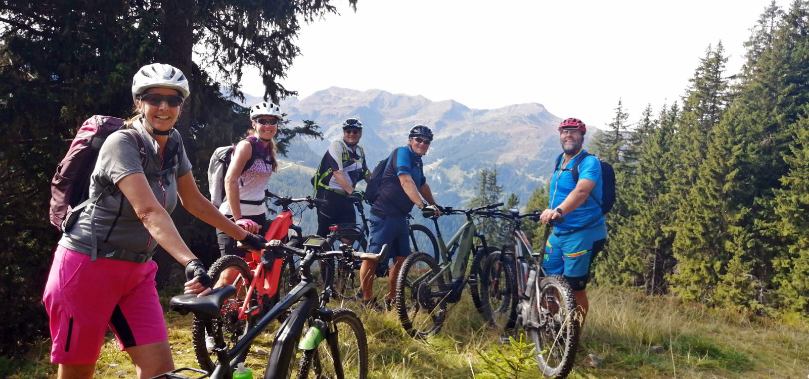 Gruppe von Mountainbikern mit E-Bikes vor Bergkulisse in der Wildschönau