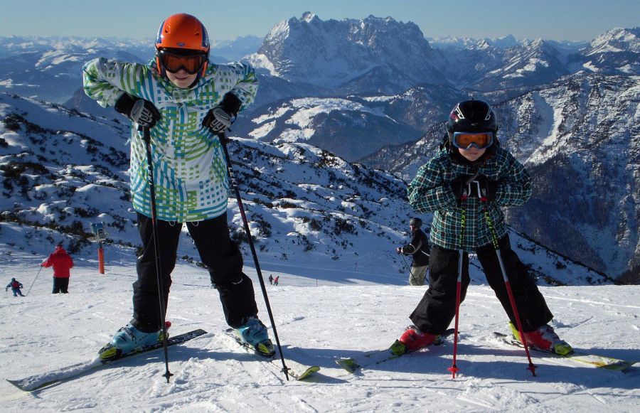 Kinder beim Skifahren mit beeindruckendem Alpenpanorama im Hintergrund