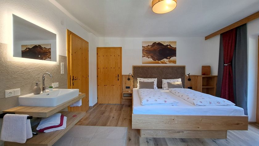 Schlafzimmer im Appartement Schönangeralm mit Doppelbett, Waschbereich und Holzambiente