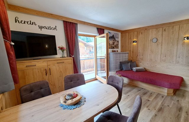 Heller Wohnbereich im Appartement Schönangeralm mit Esstisch, TV, Liege und Balkon