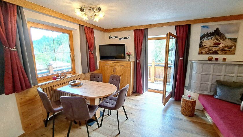 Heller Essbereich im Appartement Schönangeralm mit Holzmöbeln, TV und Balkonzugang