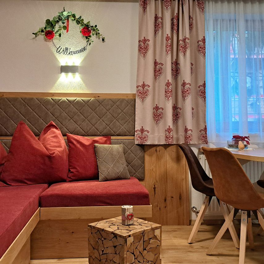 Gemütlicher Wohn- und Essbereich im Appartement Gratlspitz mit roter Sitzecke