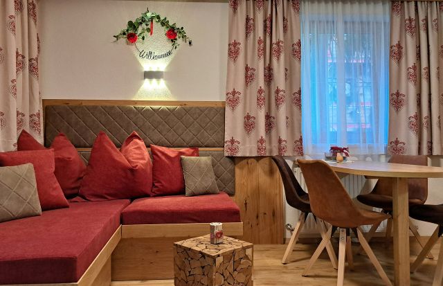 Gemütlicher Wohn- und Essbereich im Appartement Gratlspitz mit roter Sitzecke