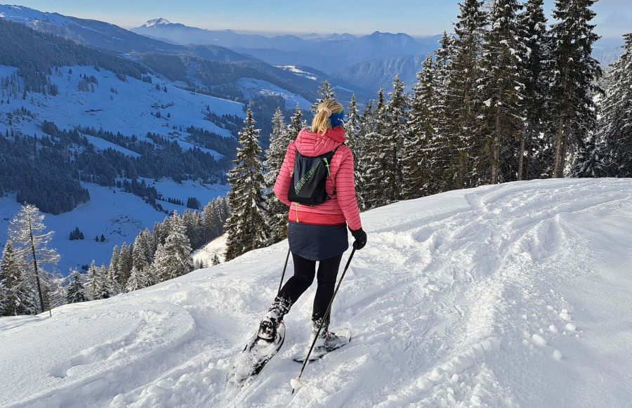 Schneeschuhwanderin auf verschneitem Bergweg mit Panoramablick in Tirol