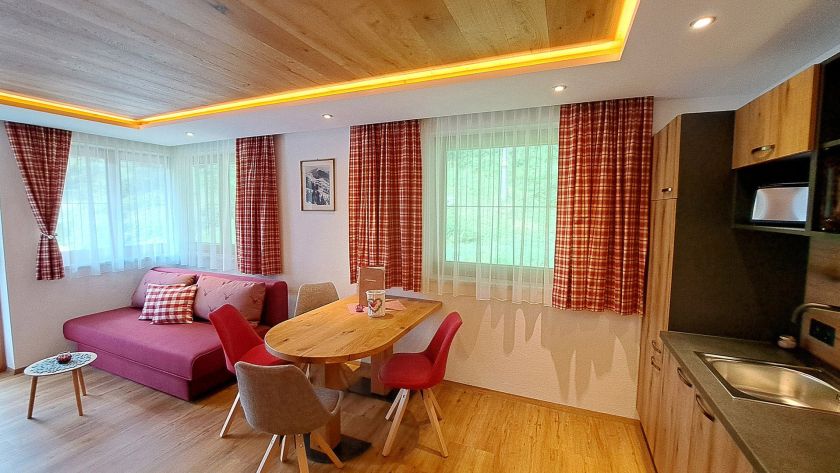 Heller Wohnbereich mit Sofa, Essecke und Küche im Appartement Feldalphorn