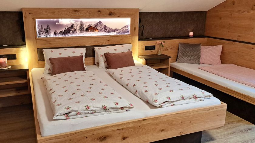 Schlafzimmer im Appartement Großer Beil mit Doppelbett, Zusatzbett und beleuchtetem Bergmotiv